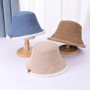 Corduroy bucket hat detail showing soft lamb wool trim and neat stitching on wooden display.