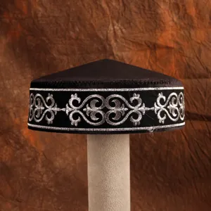 Close-up of a traditional Kazakh style black embroidered cap with intricate silver patterns.