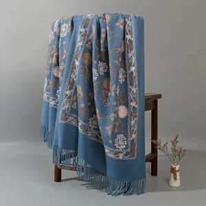 Detailed view of blue embroidered cashmere-feel winter scarf with floral pattern and tassels.