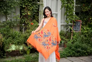 Exquisite paisley embroidery detail on orange cashmere-feel shawl with elegant tassels.