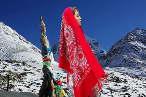 Detailed view of red winter scarf with sunflower embroidery and warm tassels outdoors.