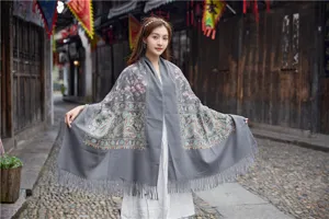 Detail view of grey ethnic style embroidered cashmere-feel shawl with fringe and floral patterns.