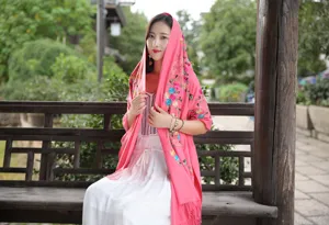 Detail shot of women's ethnic embroidered cashmere shawl scarf in bright pink with tassels.