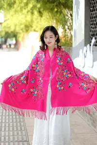 Detail shot of a vibrant pink cashmere shawl featuring exquisite colorful floral embroidery.