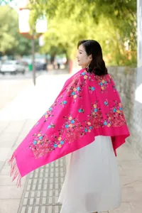 Detailed shot of ethnic floral embroidered cashmere shawl scarf in bright pink with tassels.