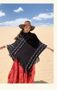 Detail view of ethnic retro black knitted poncho with colorful geometric patterns and tassel hem.