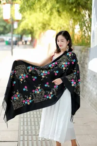 Exquisite embroidered cashmere scarf detail, featuring colorful floral patterns and soft tassel edge.