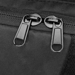 Detail view of black motorcycle backpack dual metal zippers and durable waterproof fabric.