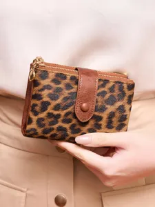 Close-up of women's short leopard print wallet featuring double zippers and snap buckle detail.