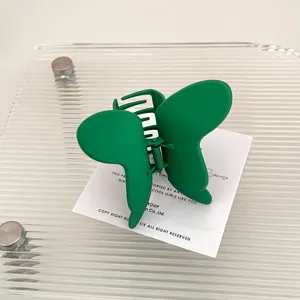 Dettaglio di un fermaglio per capelli a farfalla in metallo verde con finitura opaca.