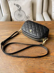 Mini quilted black crossbody bag with gold chain strap and chic camellia flower detail.