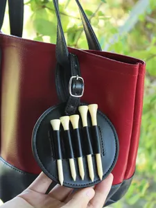 Portable round PU leather golf tee holder storage case with five wooden tees for sports use.