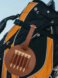 Portable brown PU leather golf tee holder case, round storage bag with multiple slots for tees.