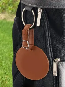 Detail close-up of a portable round brown PU leather golf tee storage pouch with metal buckle.