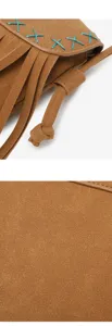 Vue rapprochée du sac bandoulière en suédine marron avec franges et détails de points bleus.