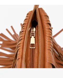 Close-up detail view of brown fringe shoulder bag featuring golden zipper and leather.