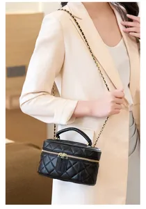 Black quilted leather vanity bag detail showing chain strap and gold hardware zipper.