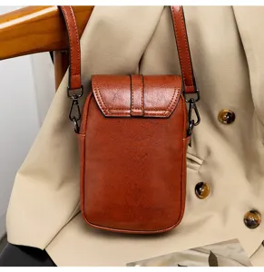 Detailed close-up view of vintage brown PU leather mini crossbody bag hanging on a beige blazer.