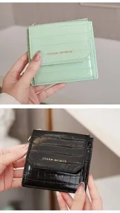 Vue détaillée d'un portefeuille compact pour femme en croco avec inscription dorée.