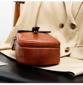 Detailed close-up of brown PU leather vintage small crossbody bag showing leather texture.