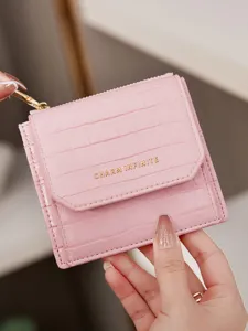 Portefeuille court pour femme rose motif croco avec lettrage métallique chic.