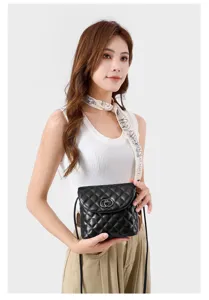 Black quilted crossbody bag detail showing classic minimalist design and metal clasp.