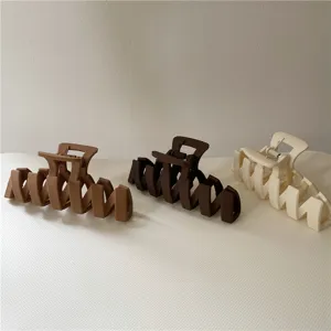 Close-up detail of matte hollow hair claw clips in three neutral colors for styling.