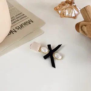 Detail shot of sweet hairpin featuring black bow, pearl accents and fabric wrapped clip.