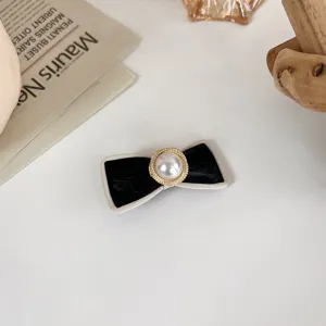 Elegant black and white bow hair clip with a large pearl center for sweet daily hairstyles.