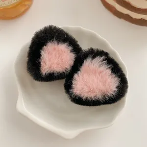 Nahaufnahme süßer schwarzer und rosa Plüsch-Katzenohren-Haarspangen, weiche flauschige Textur.