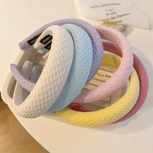 Gros plan de serres-tête larges et rembourrés en tissu gaufré de multiples coloris pastel.