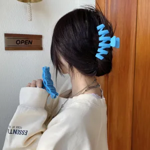 Dettaglio del morsetto per capelli opaco blu per acconciature eleganti e presa sicura.