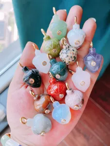Close up of natural gemstone acorn shaped pendants inlaid with cubic zirconia and gold bails.