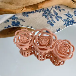 Primo piano del fermacapelli rosa opaco con design floreale romantico su superficie a specchio.