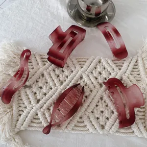 Detailed close-up view of frosted burgundy hair claw clips and banana clips on a woven mat.