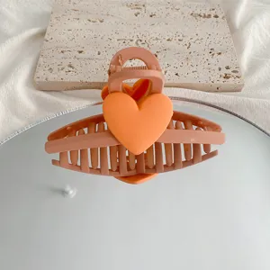 Detailed closeup of a cute macaron orange heart hair claw clip, stylish back hair shark clip.