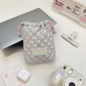 Gray polka dot quilted drawstring storage bag detail shot, soft fabric makeup pouch scene.