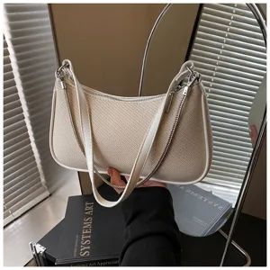 Beigefarbene Schultertasche mit weißem Lederbesatz und Kettengriem, modisches Accessoire.