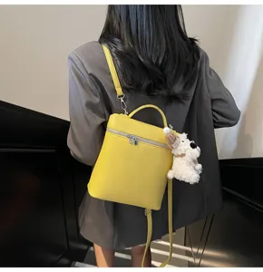Detail view of the yellow litchi pattern backpack featuring a cute puppy plush pendant.