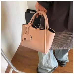 Detailed shot of the pink soft leather handbag with elephant charm, casual design texture.