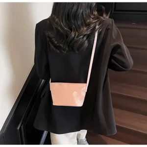 Detailaufnahme einer stilvollen rosa geprägten Eimer-Umhängetasche mit schwarzem Blazer.