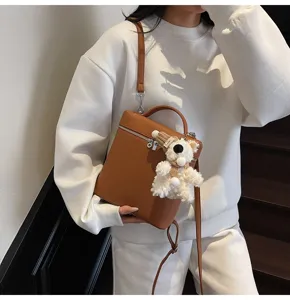 Detailed view of the stylish brown litchi grain shoulder bag with cute white bear pendant.
