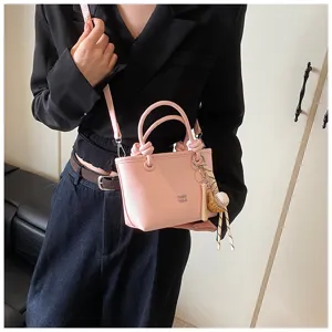 Elegante borsa a tracolla rosa da donna con manici annodati e ciondolo per ogni giorno.