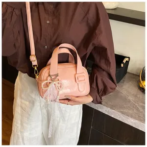 Pink soft leather shoulder bag for women, stylish crossbody pillow bag with pearl bow pendant.
