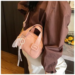 Close-up detail of a pink patent leather pillow bag with elegant lace pearl pendant and buckle.