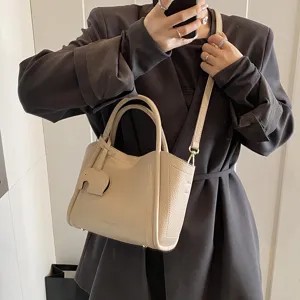 Chic faux leather bucket bag for women, stylish crossbody handbag with top handle and cute charm.
