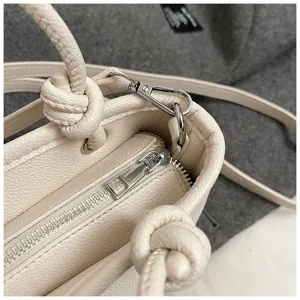 Vista dettagliata della borsa a tracolla beige da donna, con chiusura a zip e manico con nodo.