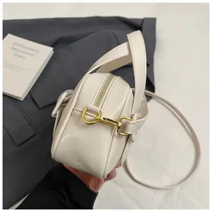Close-up detail of the white soft leather shoulder bag showing gold metal hardware and side zipper.