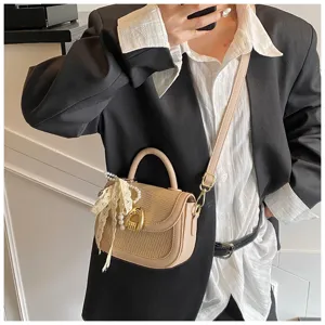 Detalle del bolso cruzado tejido con elegante colgante de perlas y cierre metálico elegante.
