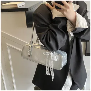 Silver baguette shoulder bag with white lace bow and heart charm, stylish detail view.